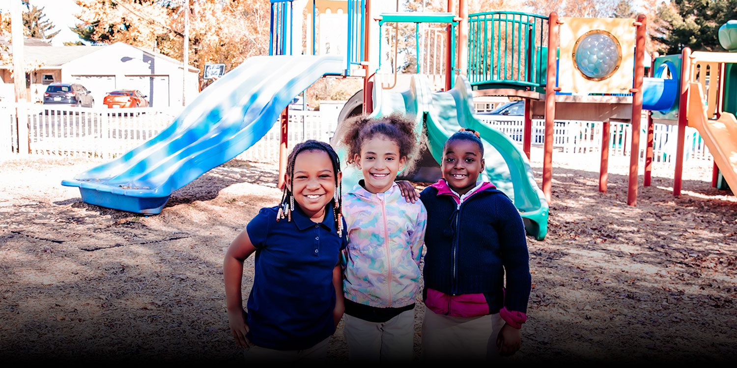 Smiling students standing together on school playground.